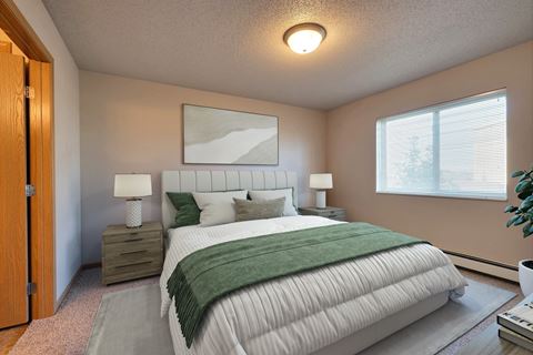 a bedroom with a white bed and a green blanket. Fargo, ND East Bridge Apartments