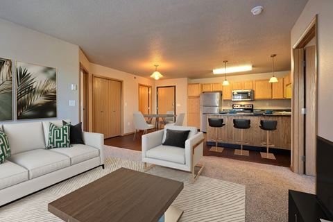 a living room and kitchen with a couch and a table. Fargo, ND East Bridge Apartments