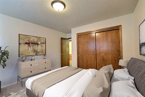 a bedroom with a bed and a dresser. Fargo, ND Emerald Apartments