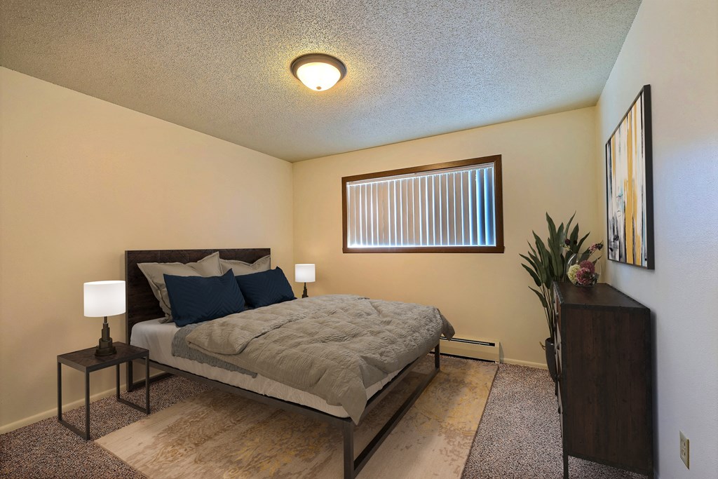 a bedroom with a bed and a window. Fargo, ND Emerald Apartments