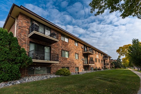 a brick building with three levels and a sidewalk in front. Fargo, ND Emerald Apartments