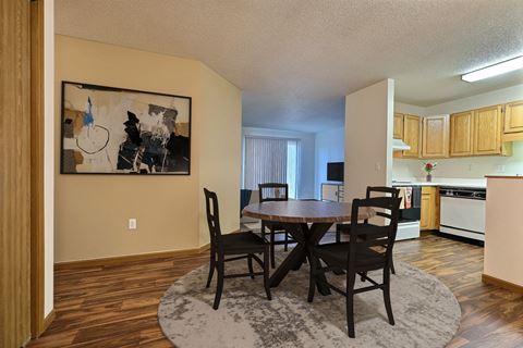 Fargo, ND Flagstone Apartments. a dining area with a table and chairs and a kitchen in the background