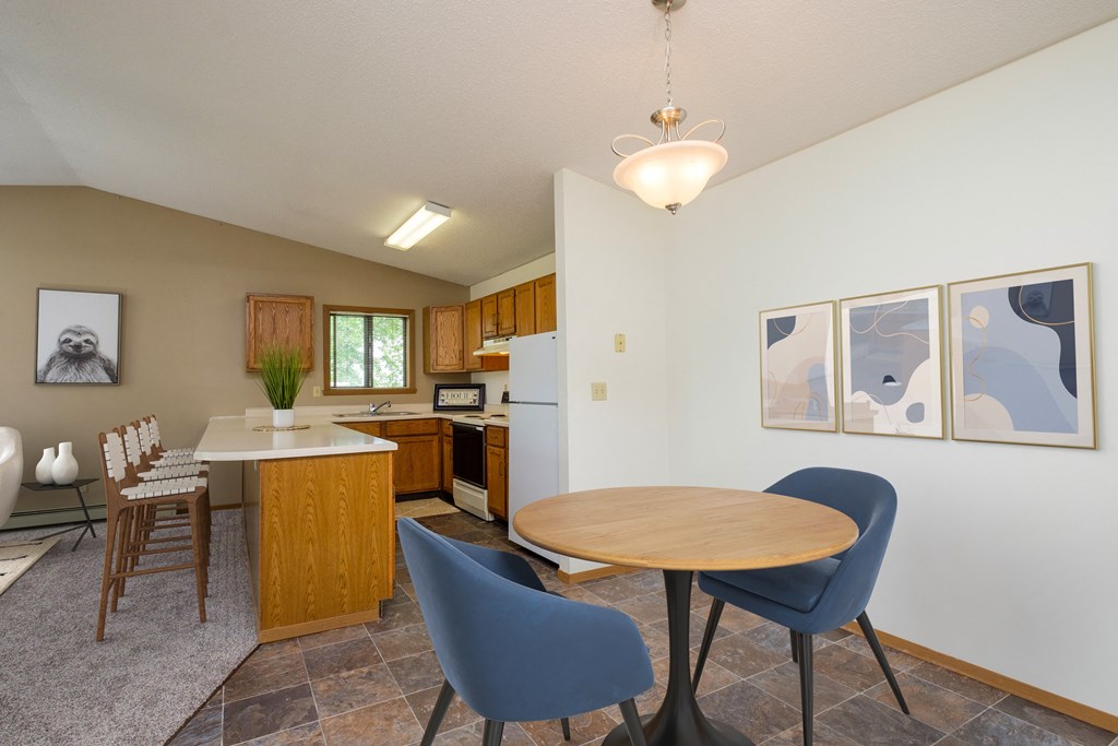 Fargo, ND Flickertail Apartments a dining area with a small table and chairs and a kitchen in the background