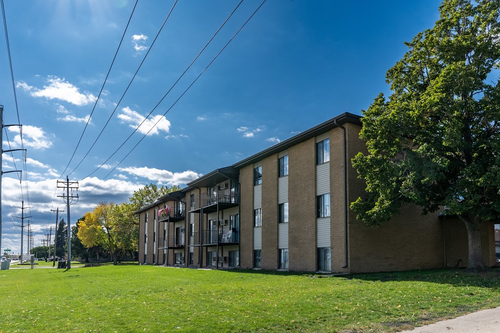 a large brick apartment building with a green grass in front. Fargo, ND France Apartments