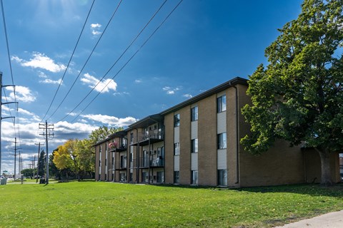 a large brick apartment building with a green grass in front at France, North Dakota