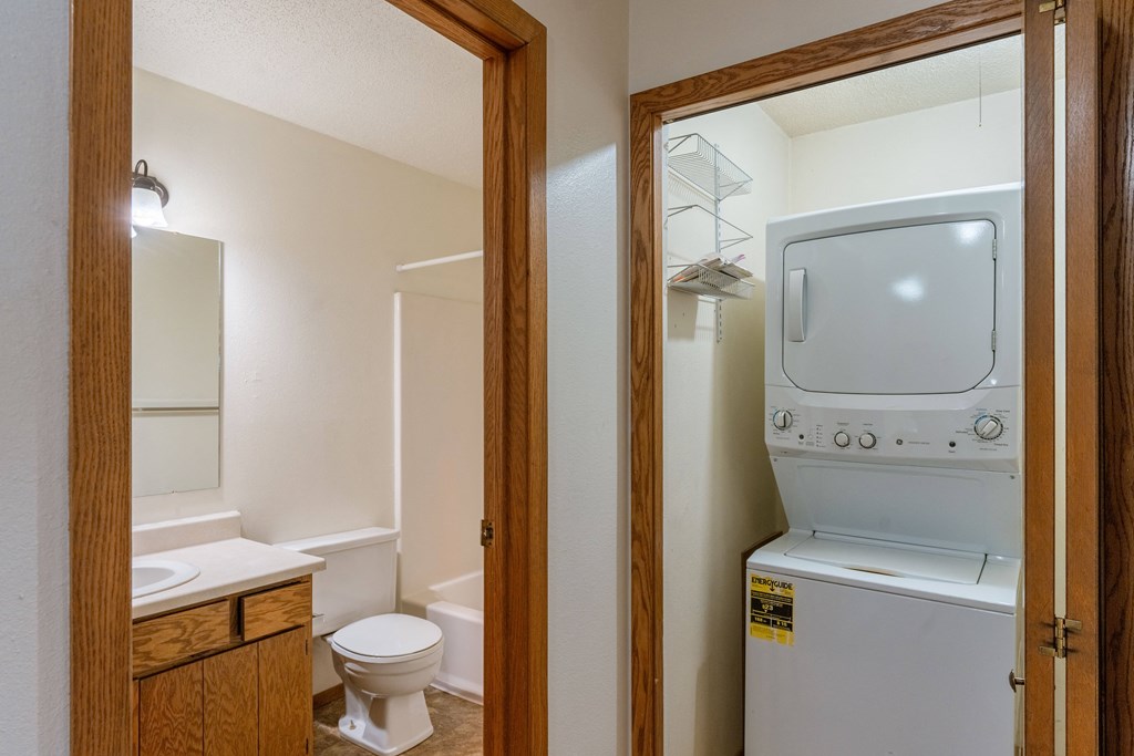 a bathroom with a washer and dryer in it and a toilet and sink. Fargo, ND Galleria Apartments