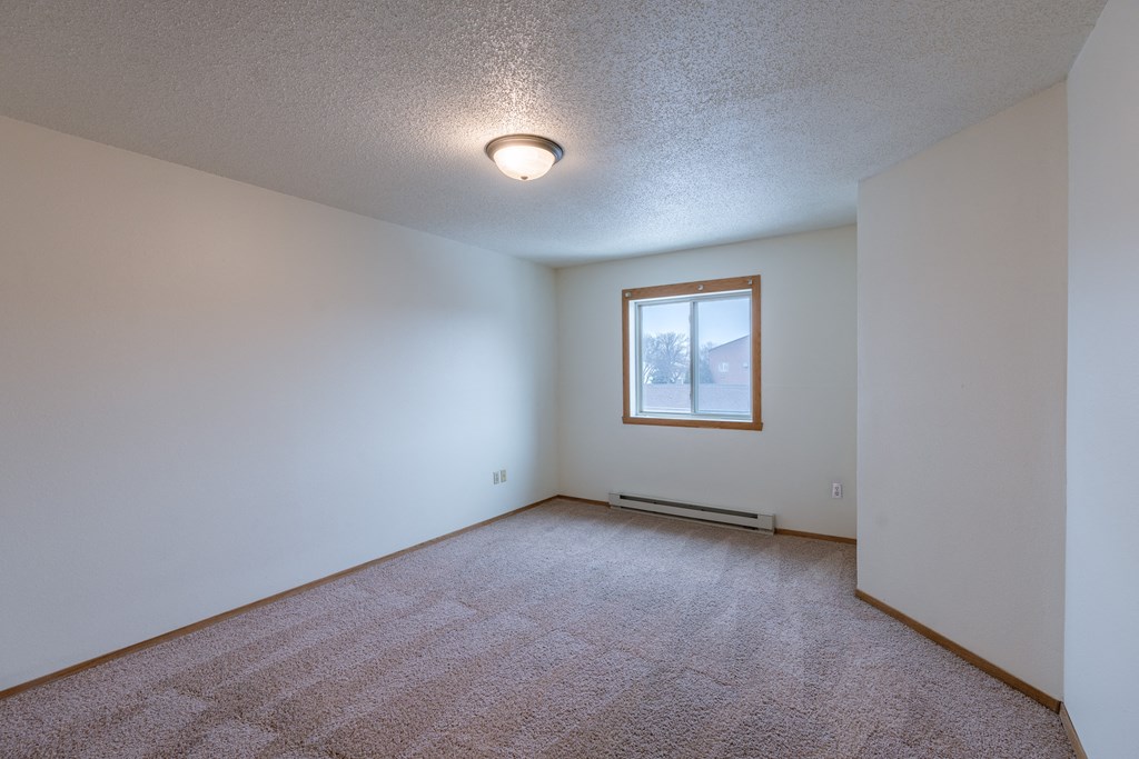 a bedroom with white walls and a window. Fargo, ND Galleria Apartments