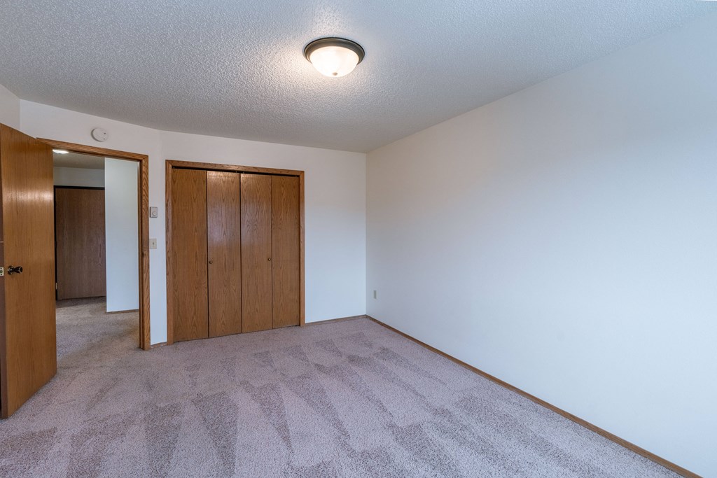 a bedroom with white walls and a door to a closet. Fargo, ND Galleria Apartments