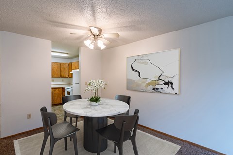 a dining room with a table and chairs and a ceiling fan. Fargo, ND Galleria 3 Apartments