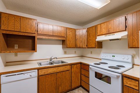 an empty kitchen with white appliances and wooden cabinets. Fargo, ND Galleria 3 Apartments