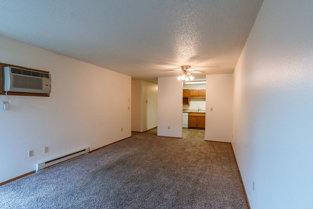 an empty living room with carpet and a ceiling fan. Fargo, ND Galleria 3 Apartments