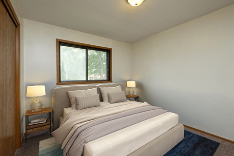Fargo, ND Gemstone Apartments. A bedroom with a bed and two night stands and a window.