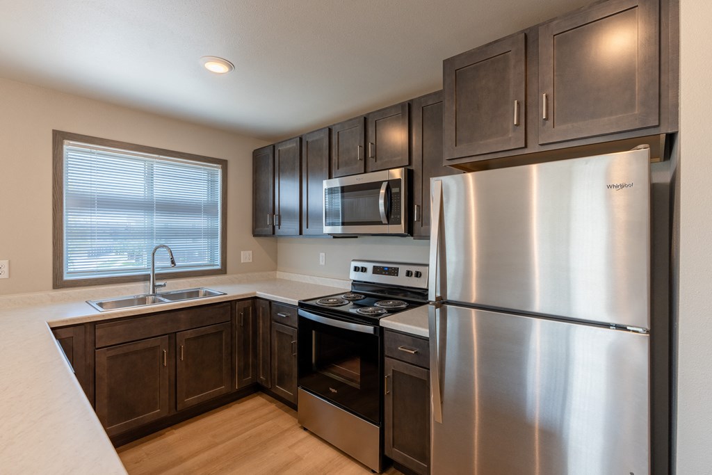 An updated kitchen with stainless steel appliances and dark wood cabinets. Fargo, ND Granger Court Apartments.