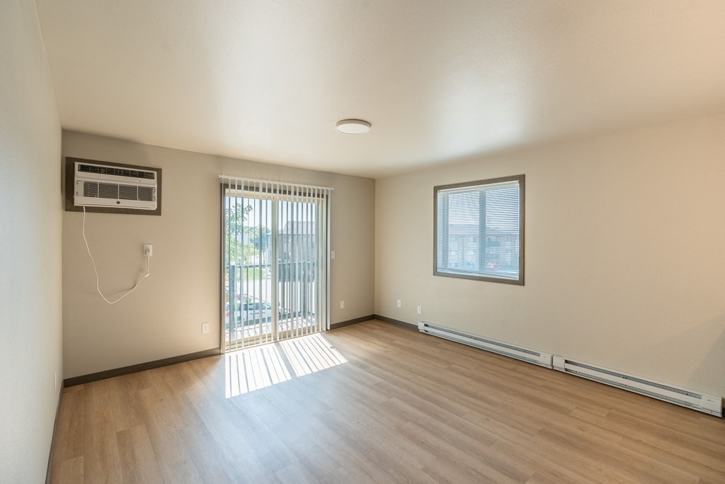 An empty living room with wood floors and a sliding glass door. Fargo, ND Granger Court Apartments