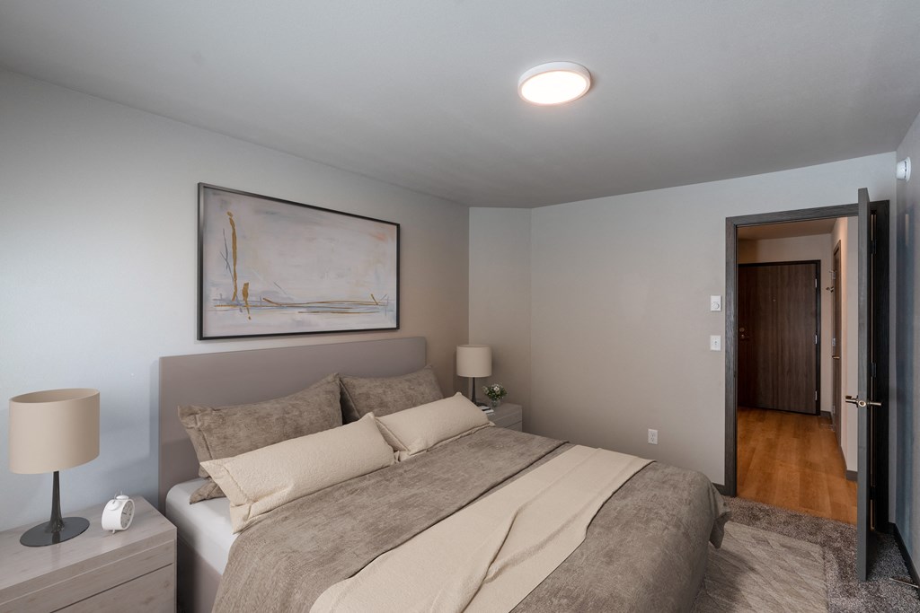 a bedroom with a bed and a door to the hallway. Fargo, ND Granger Court Apartments