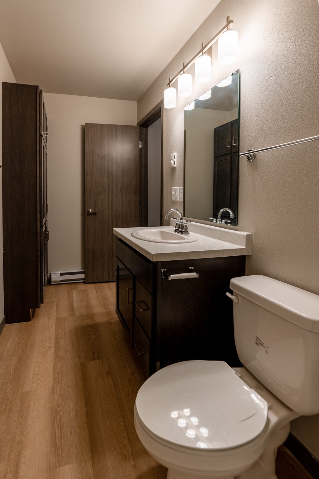 A bathroom with a toilet and a sink and a mirror. Fargo, ND Granger Court Apartments.