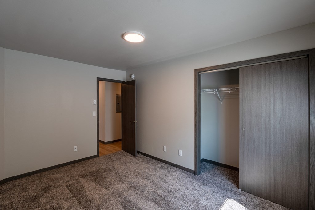 An empty room with a closet and a door to a wardrobe. Fargo, ND Granger Court Apartments.
