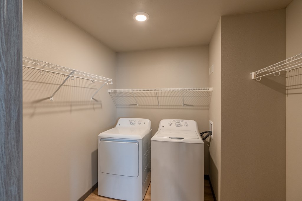 A laundry room with two washes and a dryer in it and a closet. Fargo, ND Granger Court Apartments.