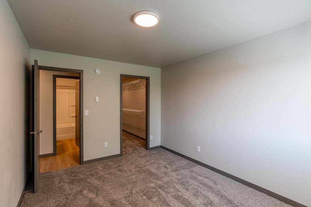 A bedroom with a door to a bathroom and a closet. Fargo, ND Granger Court Apartments.