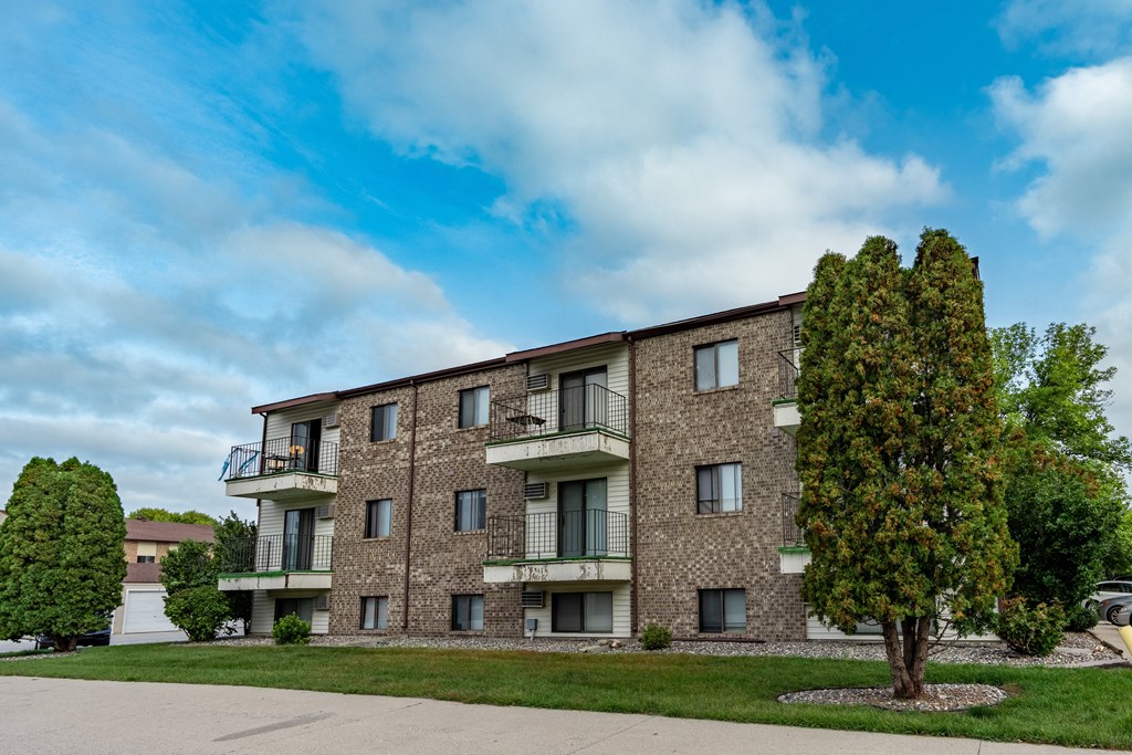a brick apartment building with balconies and a tree. Fargo, ND Hawthorn Apartments