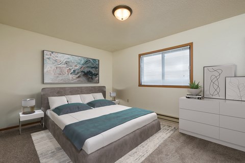Fargo, ND Hunters Run Apartments. A bedroom with a bed, dresser, and large window.