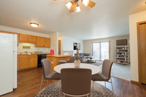 Fargo, ND Hunters Run Apartments. A dining area with a table and four chairs and a kitchen in the background.