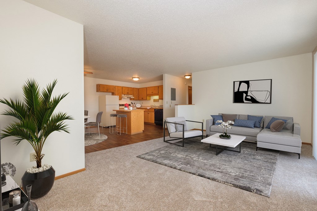 Fargo, ND Hunters Run Apartments. A living room with a couch, table, and four chairs and a kitchen in the background.