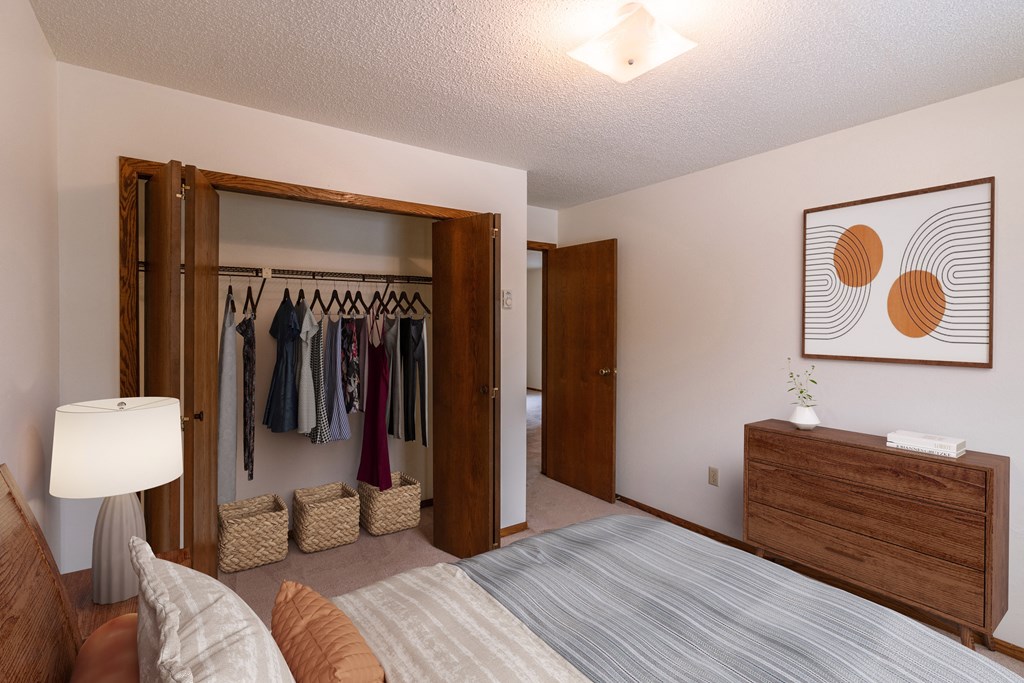 a bedroom with a closet and a bed and a dresser. Fargo, ND Huntington Apartments