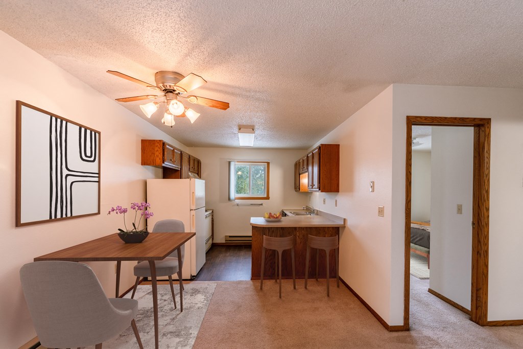 a dining room and kitchen with a table and chairs and a ceiling fan. Fargo, ND Huntington Apartments