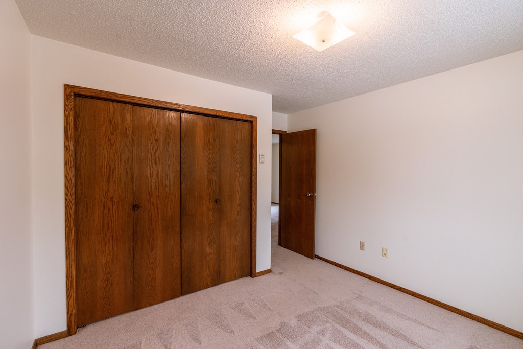A bedroom with a closet. Fargo, ND Huntington Apartments.