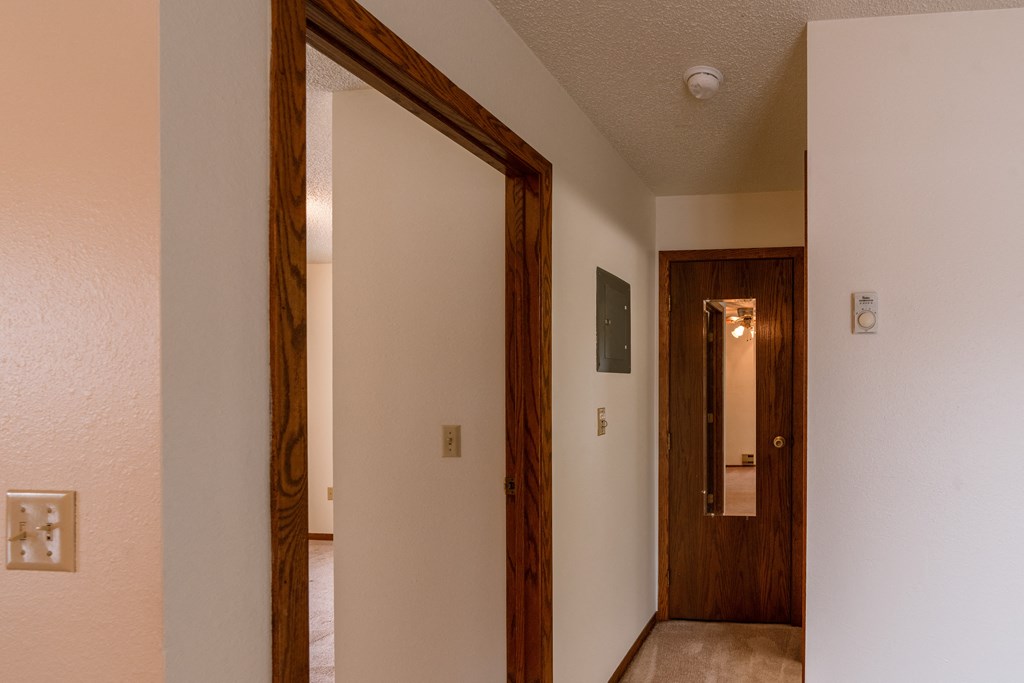 The view of the hallway from the living room with the door open to the bathroom and bedroom with a closet door with a mirror. Fargo, ND Huntington Apartments.