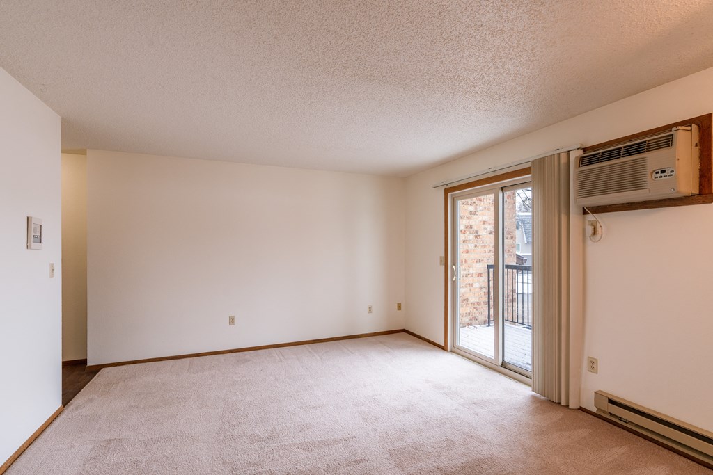 an empty living room with a sliding glass door to a balcony