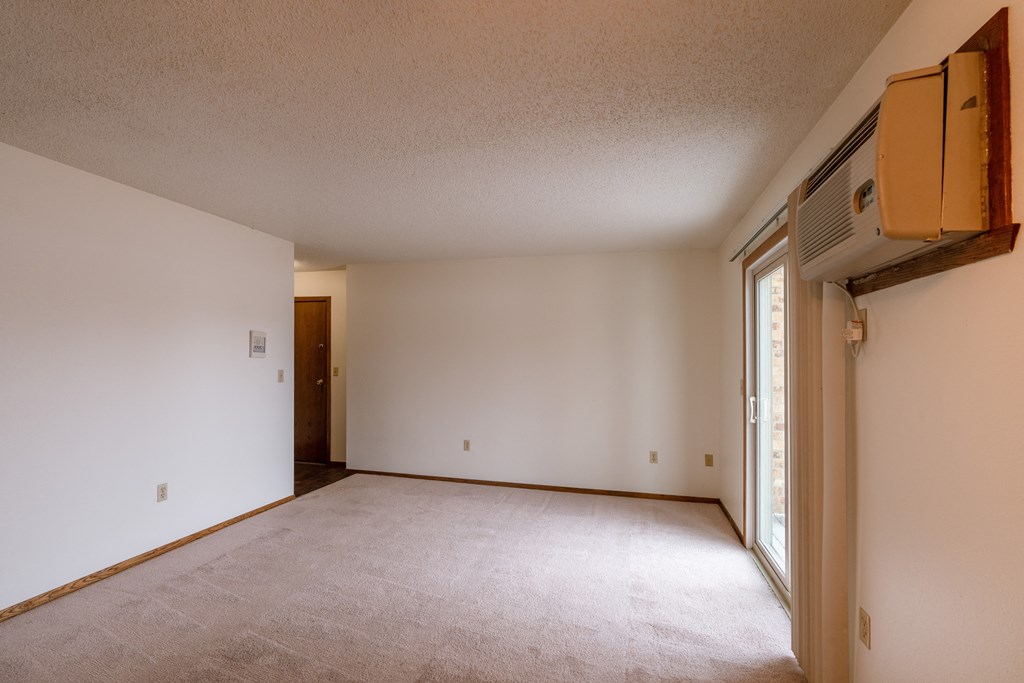 A empty living room with white walls and a window. Fargo, ND Huntington Apartments.