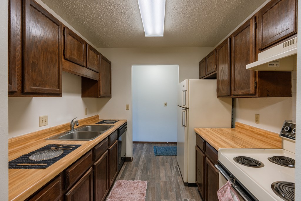 a kitchen with wood cabinets and white appliances and a refrigerator. Fargo, ND Jadestone Apartments