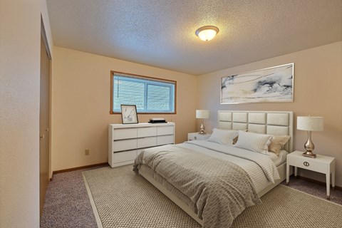 a bedroom with a bed and a dresser. Fargo, ND Kennedy Apartments