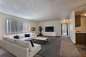 Fargo, ND Kingswood Apartments. A living room with a large white couch and a coffee table. A long window brightens the room with natural light