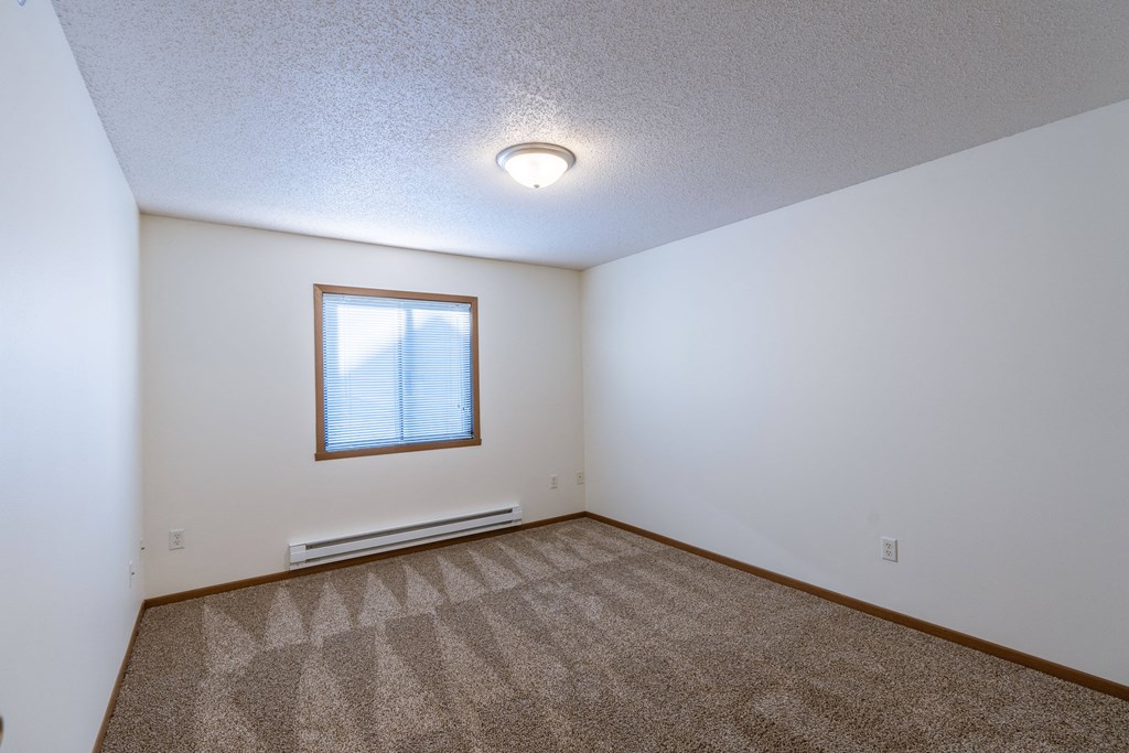 a bedroom with carpet and a window. Fargo, ND Lake Crest Apartments