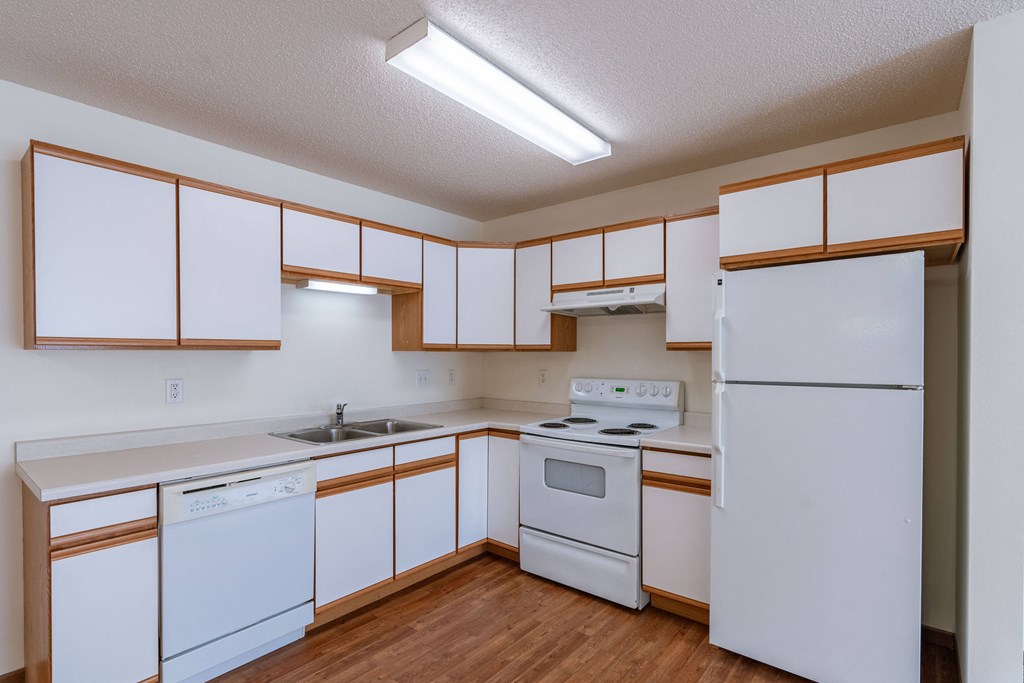 a kitchen with white appliances and white cabinets. Fargo, ND Lake Crest Apartments