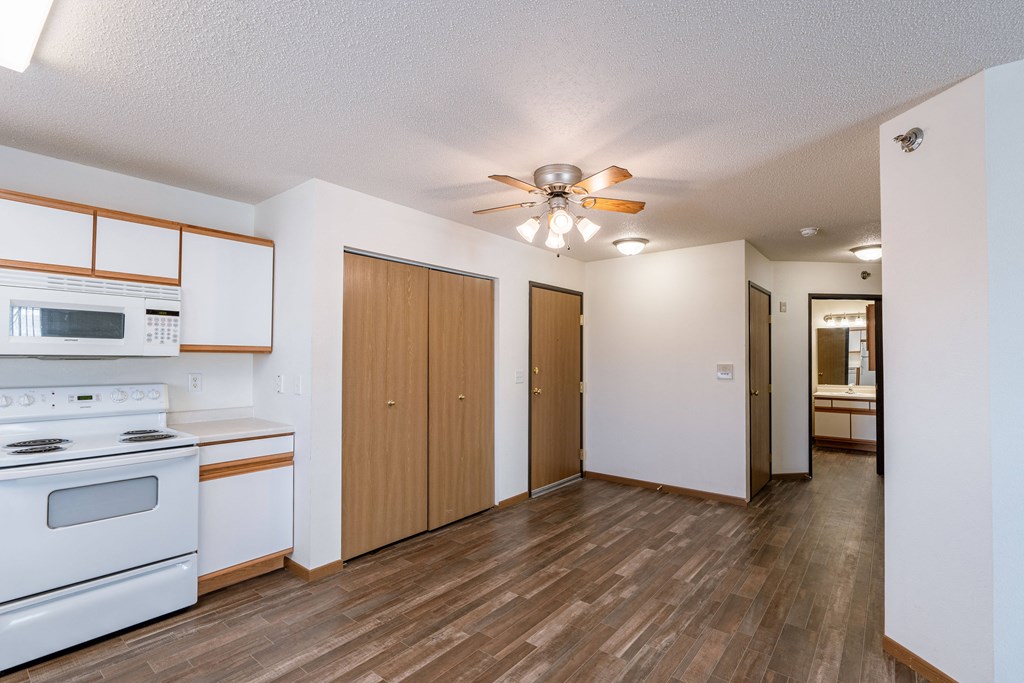 an empty kitchen with white appliances and a ceiling fan. Fargo, ND Lake Crest Apartments