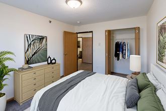 Fargo, ND Lake Crest Apartments. A bedroom with a large bed and a dresser with a mirror