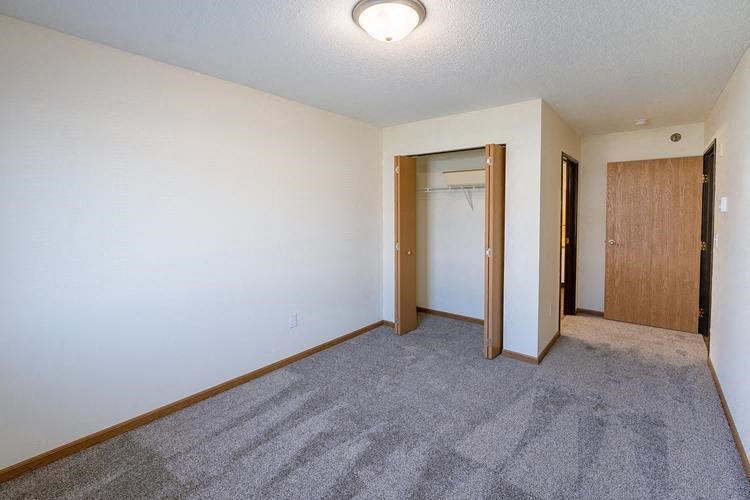Fargo, ND Lake Crest Apartments. A bedroom with a carpeted floor and a door to a closet