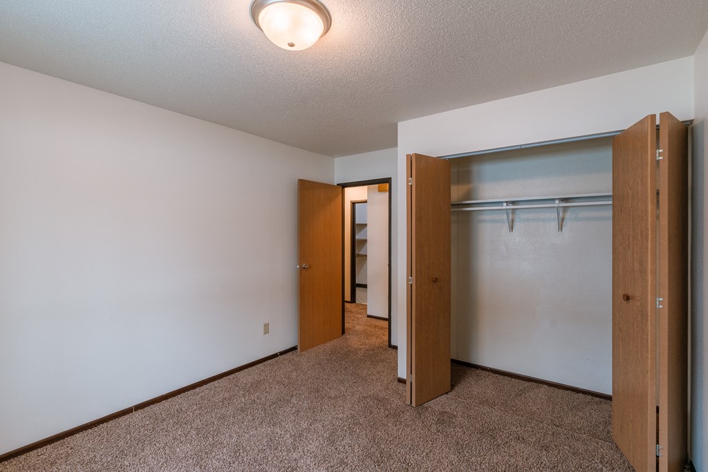 An empty bedroom with a closet and a mirrored closet door. Fargo, ND Long Island Apartments.