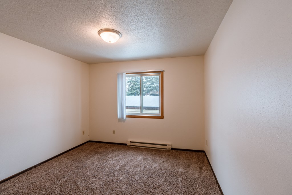 a bedroom with a window and carpeted floors. Fargo, ND Long Island Apartments.