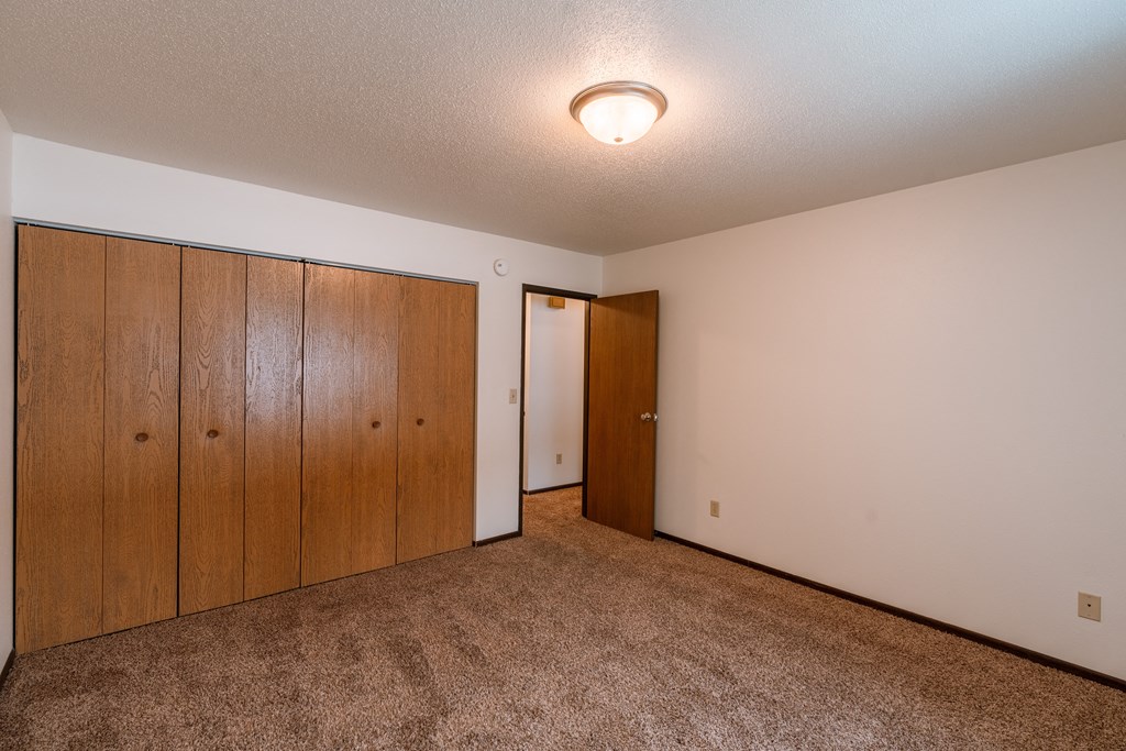 A spacious bedroom with carpeted floors a large closet. Fargo, ND Long Island Apartments.