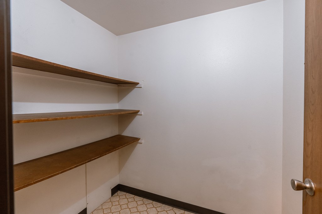 A small room with shelves and a door. Fargo, ND Long Island Apartments.
