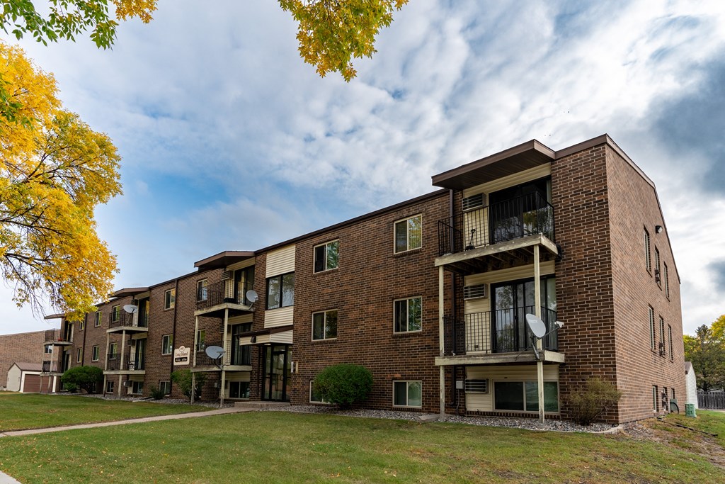A brick apartment building with balconies on a cloudy day. Fargo, ND Long Island Apartments.