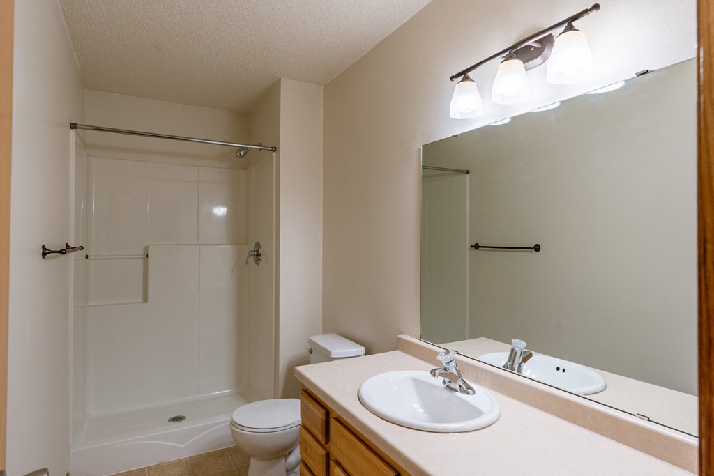 a bathroom with a sink and a toilet and a shower. Moorhead, MN Mallard Creek Apartments