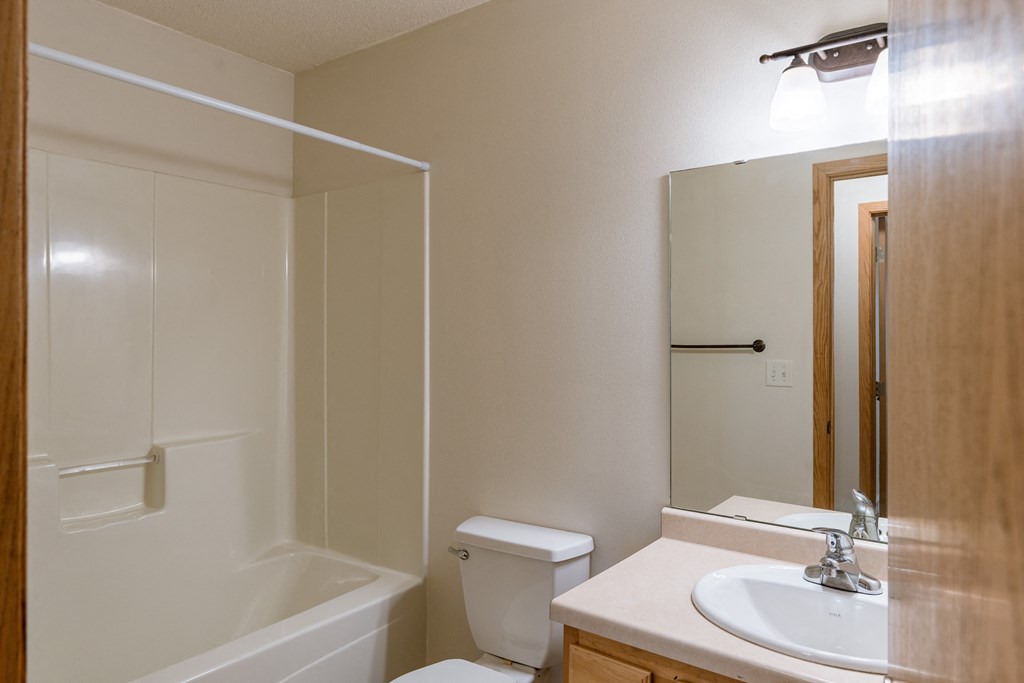 a bathroom with a sink and a toilet and a shower. Moorhead, MN Mallard Creek Apartments