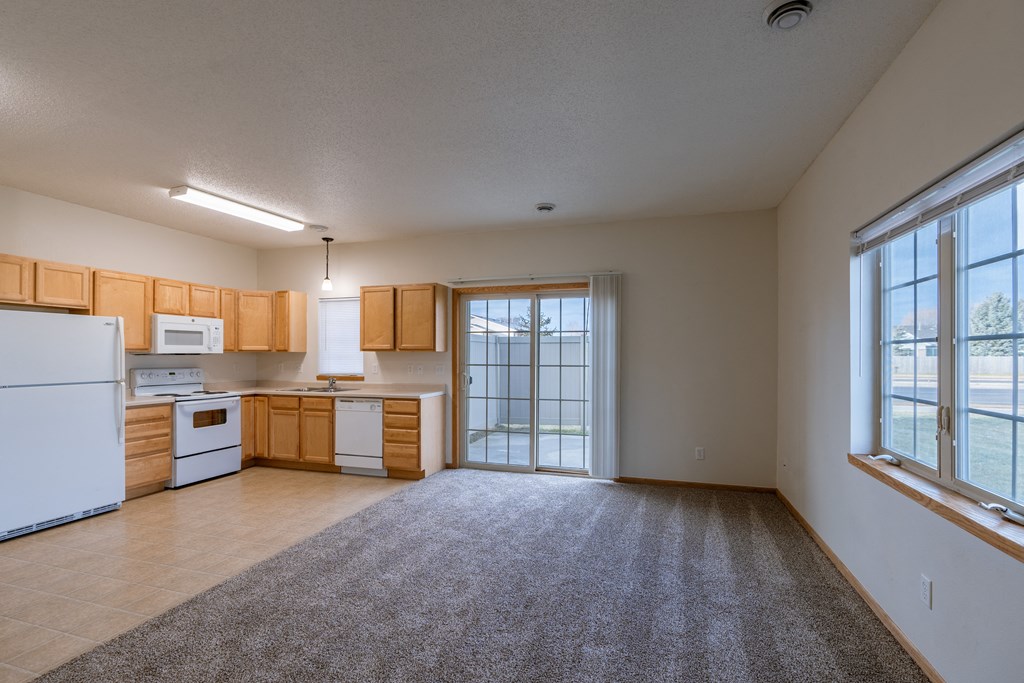 a kitchen and living room with a window and sliding glass door. Moorhead, MN Mallard Creek Apartments