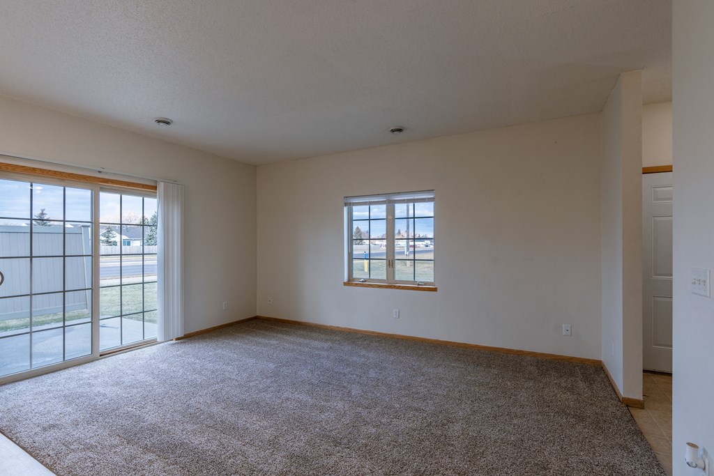 a living room with a window and a glass sliding door. Moorhead, MN Mallard Creek Apartments